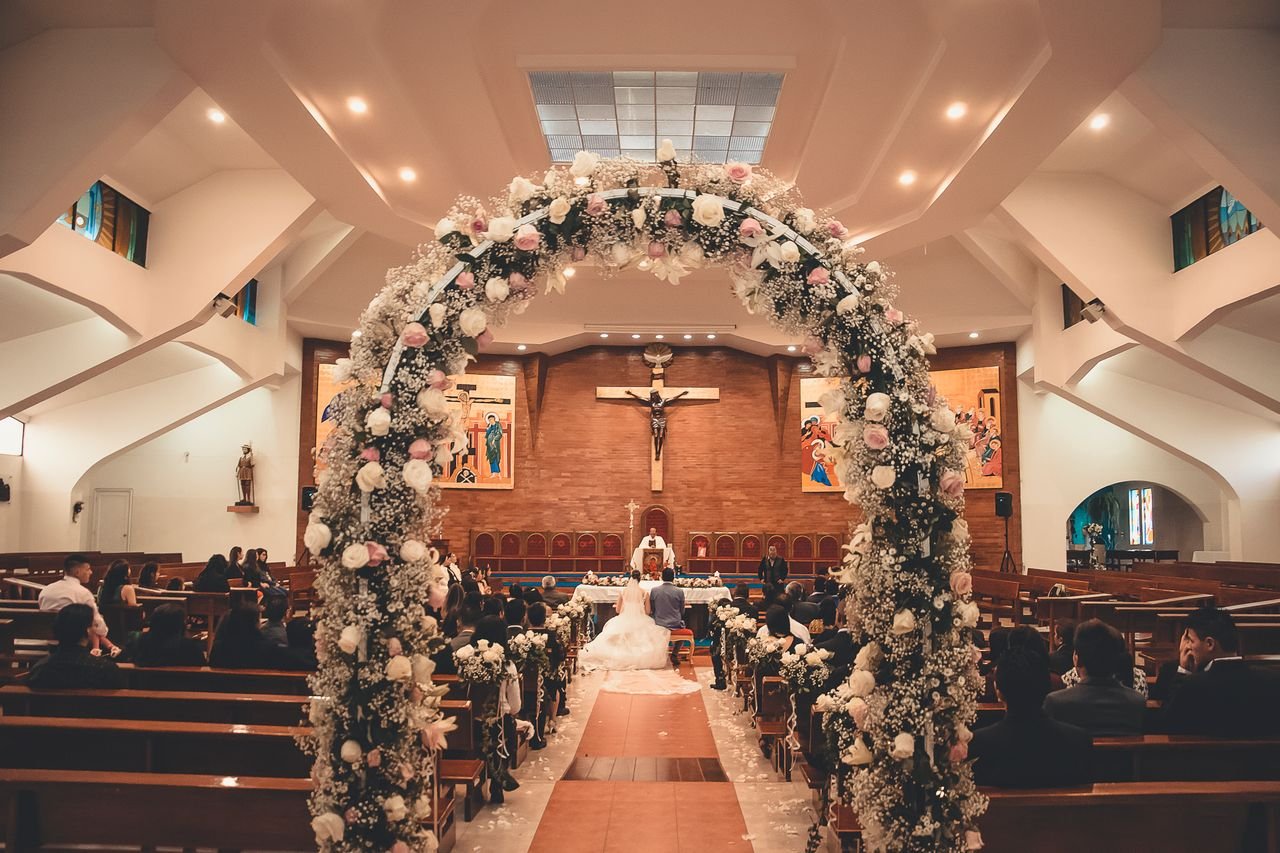 why-choose-us A captivating wedding ceremony inside a church featuring a floral archway and seated guests.