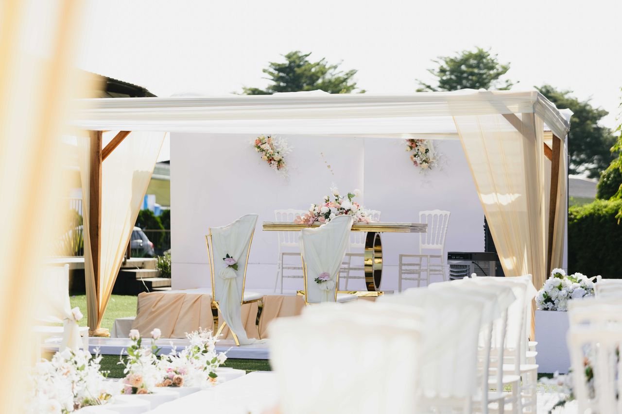 about-02 Beautiful outdoor wedding ceremony setting with white and pastel-colored decor and floral arrangements.